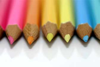 A line of brightly coloured pencils. Close-up shot of the pointed ends.