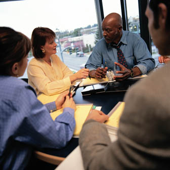 Business meeting at a conference table.Focus of the shot is on an African Caribbean man and a caucasian woman.